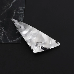Macro detail of silver geometric triangle hair clip with textured hammered metal finish