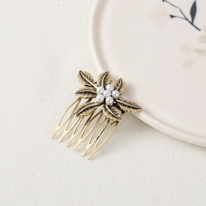 Detailed macro view of vintage gold hair comb featuring metal leaves and white pearls