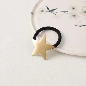 Macro shot of minimalist black elastic hair tie with a matte gold star charm detail