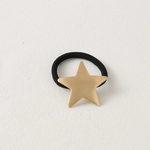 Detail of a black elastic hair tie featuring a matte gold pentagram star charm