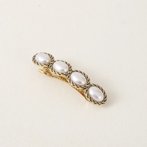 Vintage hair clip with four white oval pearls on an engraved gold-toned metal base