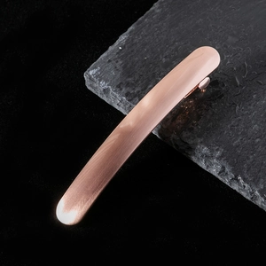 Détail d'une pince à cheveux en métal brossé or rose montrant la texture mate sur pierre