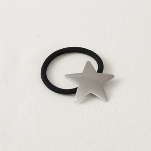 Close-up of black elastic hair tie with a matte silver star charm on a white surface