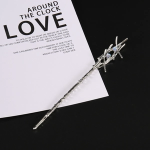 Detail of liquid metal hair pin with iridescent blue beads on a punk style wand