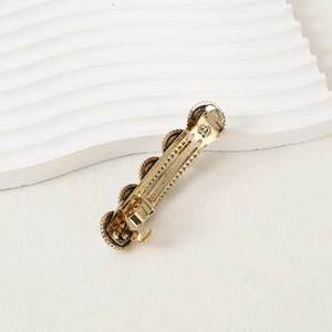 Close-up of golden vintage hair clip featuring embossed patterns and spring-loaded mechanism