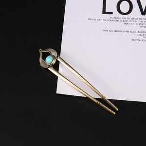 Close-up of vintage gold U-shaped hairpin featuring a teardrop frame with a turquoise bead