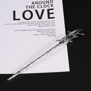Macro detail of silver magic wand hair pin with irregular lava texture and blue gemstone