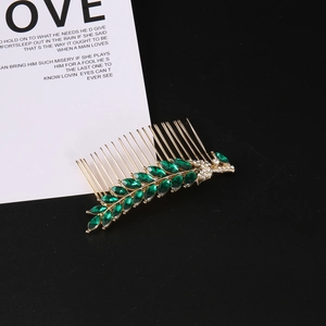 Detailed close-up of golden leaf hair comb with green marquise stones and sparkling crystals