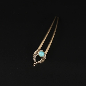 Macro detail of U-shaped hair pin featuring vintage bronze alloy and turquoise stone bead