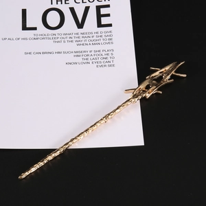 Detail of golden wand hair pin featuring hammered texture and hollow branch design