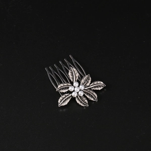 Detail of vintage silver hair comb with pearl flower design and textured metal leaves