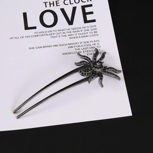 Detailed macro view of dark metal spider hair pin with sparkling black and white rhinestones