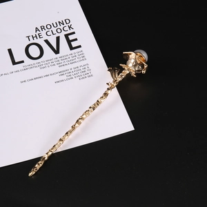 Golden rose hair pin with white pearl and branch texture on elegant black background