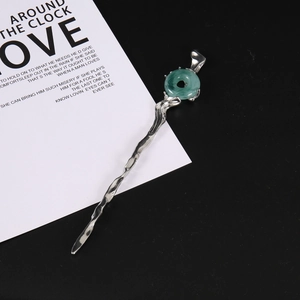 Détail d'une épingle à cheveux rétro avec pierre de jade verte et texture argentée