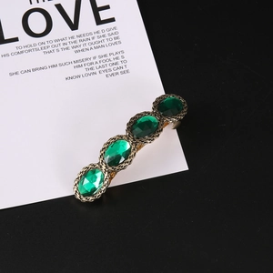Vintage gold hair clip with emerald green gemstones and engraved chain texture