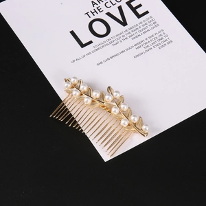 Detail of leaf design gold hair comb with elegant white pearls on a black background