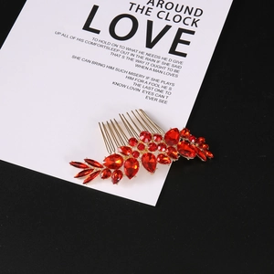 Macro detail of golden bridal hair comb featuring brilliant red crystal leaves and rhinestones