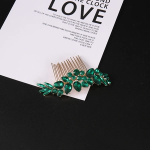 Elegant gold leaf hair comb with emerald green crystals on a sophisticated background