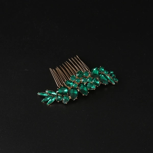 Detail view of vintage gold hair comb with emerald green leaf-shaped gemstones