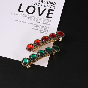 Macro detail of vintage-style gold hair clips with red and green gemstone inserts