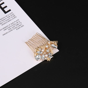 Détail d'un peigne à cheveux vintage doré orné de strass brillants et de perles blanches