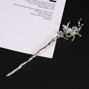 Detailed view of silver branch hair pin with three blue gemstones and vine patterns