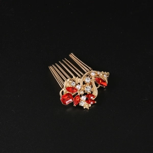Détail d'un peigne à cheveux doré avec cristaux rouges et perles élégantes au design floral