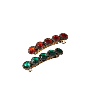 Retro style hair clips with red and green crystals set in golden alloy base on white background