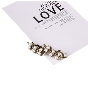 Elegant gold leaf hair clip with white pearls in a vintage minimalist design for women