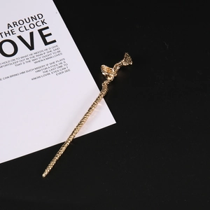 Detail view of gold-plated hair pin with hammered texture and abstract geometric design