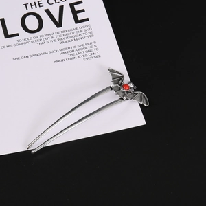 Detailed view of vintage punk bat hair pin with red gemstone and aged alloy texture