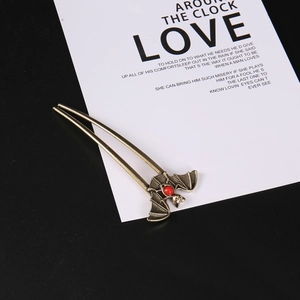 Detail of vintage bat hair pin with antique bronze finish and red gemstone inlay