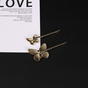 Detailed view of two gold butterfly hair clips with fine metallic wing textures on black