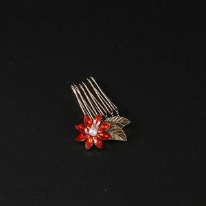 Vintage bronze hair comb with red rhinestone flower and pearl on black background