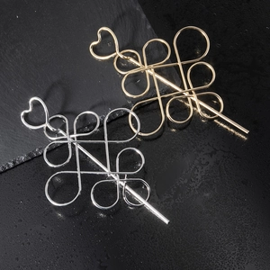 Golden and silver metal hairpins with hollow heart and knot design on dark stone