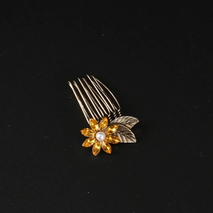 Detail shot of vintage flower hair comb with yellow rhinestones and center pearl