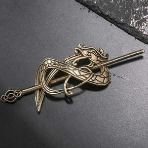 Vue détaillée d'une épingle à cheveux dragon en bronze vintage sur un socle en pierre