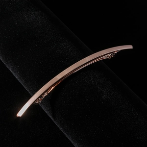 Vue macro détaillée d'une pince à cheveux en métal or rose avec une surface brossée fine