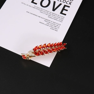 Détail macro d'une barrette en forme de feuille avec cristaux rouges et alliage doré