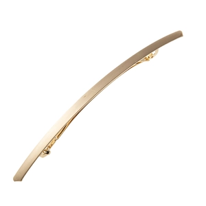 Détail d'une barrette dorée en métal brossé avec un long design incurvé élégant
