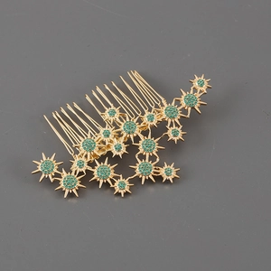Detail of elegant gold-plated seven-tooth hair comb featuring green crystal starbursts