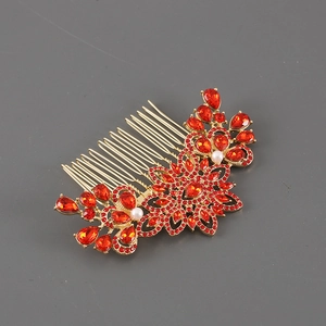 Close-up of golden hair comb with red rhinestones and floral alloy decorative details