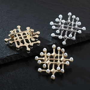 Vintage palace style pearl brooches in gold and silver finishes on a stone background