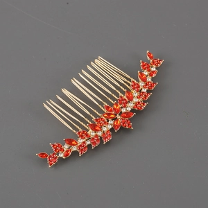 Dettaglio di un pettine per capelli dorato con strass rossi marquise e cristalli bianchi