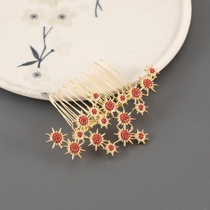 Detail of a gold alloy seven-tooth hair comb with red rhinestones and star-shaped patterns