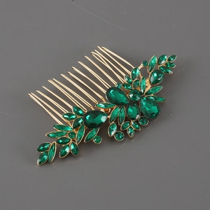 Detail of vintage gold alloy hair comb with emerald green rhinestones and leaf motif