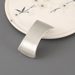 Detail of matte silver minimalist metal hair clip with brushed texture on ceramic plate