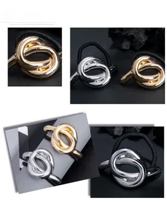 Detail of minimalist metallic knot hair tie in polished gold and silver finishes