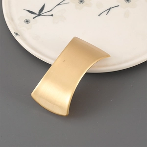 Detailed view of matte brushed gold alloy hair clip with a minimalist geometric curved shape