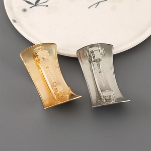 Close-up of golden and silver metal hair clips showing the spring clasp mechanism detail